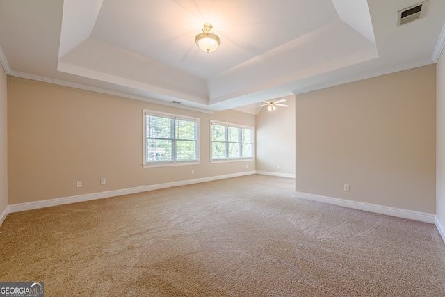 spare room with a tray ceiling, baseboards, light colored carpet, and visible vents