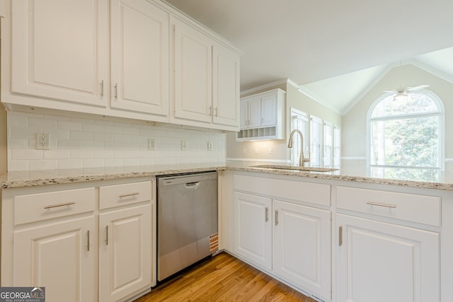 kitchen with white cabinetry, backsplash, light wood-style floors, stainless steel dishwasher, and a sink