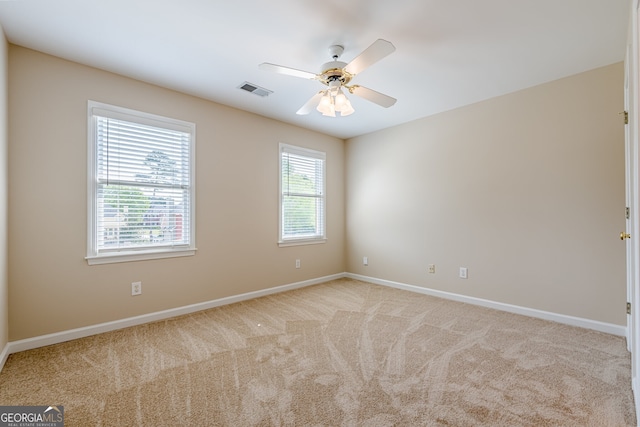 empty room with visible vents, baseboards, ceiling fan, and light colored carpet