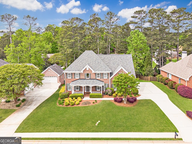 view of front of property featuring covered porch, a front yard, fence, brick siding, and concrete driveway
