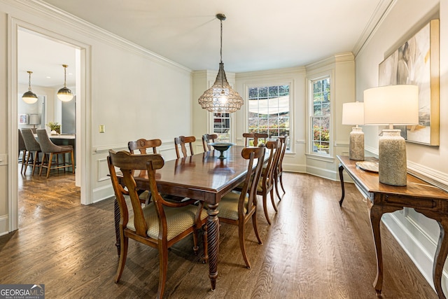 dining space featuring wainscoting, a decorative wall, ornamental molding, and dark wood finished floors