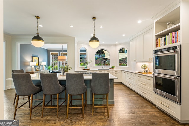kitchen with white cabinets, light countertops, double oven, and a kitchen breakfast bar