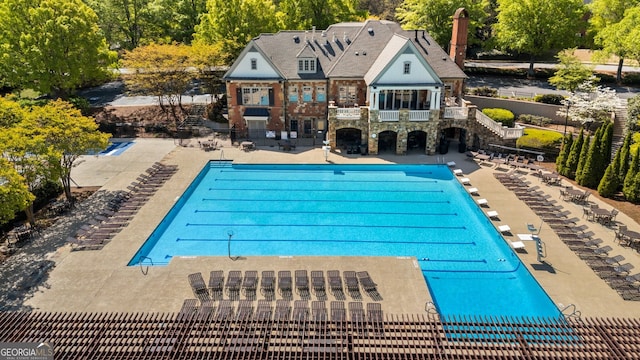 pool with a patio area, stairway, a diving board, and fence