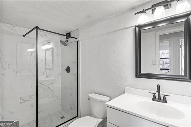 bathroom featuring toilet, a marble finish shower, and vanity