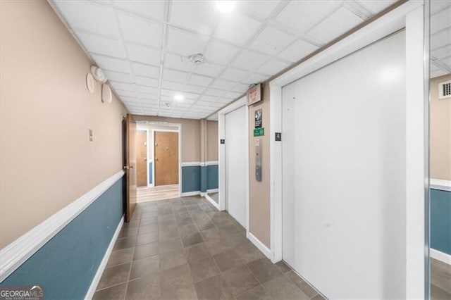 hall with visible vents, elevator, and baseboards