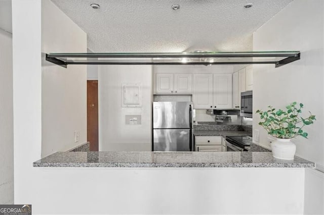 kitchen with white cabinets, a textured ceiling, a peninsula, and stainless steel appliances