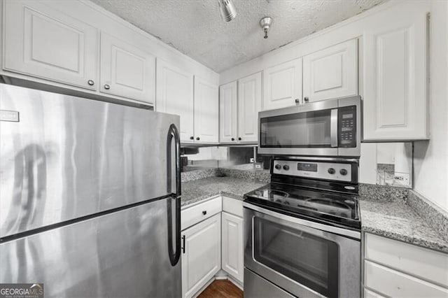 kitchen with a textured ceiling, light stone counters, white cabinetry, and stainless steel appliances