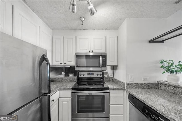 kitchen with white cabinetry, appliances with stainless steel finishes, light stone counters, and a textured ceiling