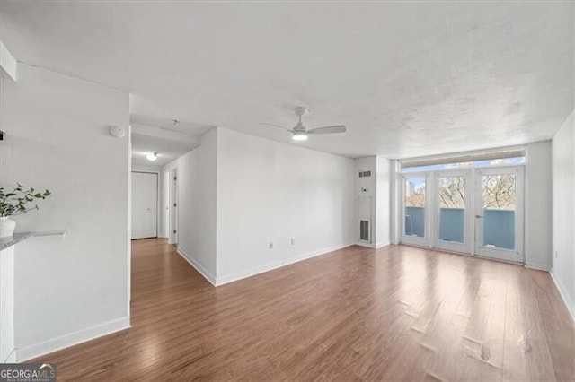 unfurnished living room featuring wood finished floors, ceiling fan, and baseboards