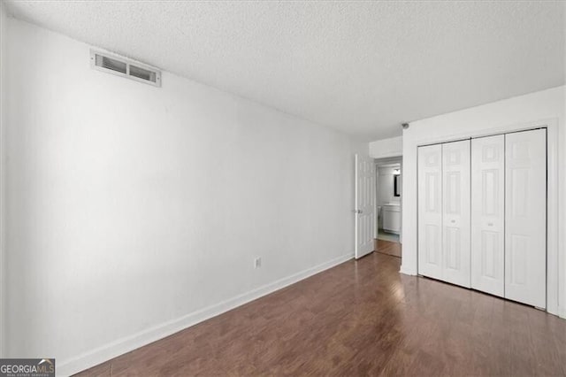 unfurnished bedroom featuring visible vents, baseboards, wood finished floors, and a textured ceiling