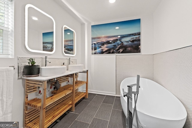 full bath featuring a soaking tub, recessed lighting, a sink, wainscoting, and double vanity