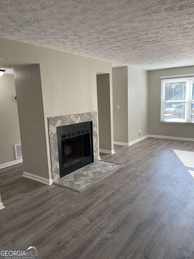 3621 Stedman Pl, Duluth, GA 30096 - unfurnished living room featuring a tiled fireplace, wood finished floors, and a textured ceiling