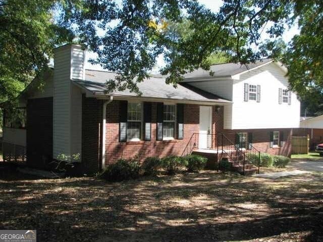 split level home featuring brick siding and a chimney