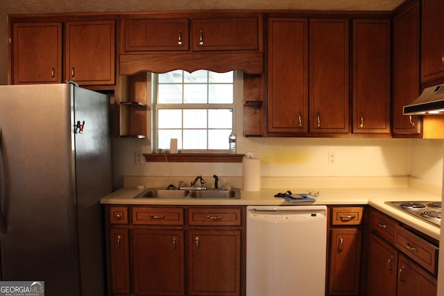 kitchen with under cabinet range hood, appliances with stainless steel finishes, a sink, and light countertops