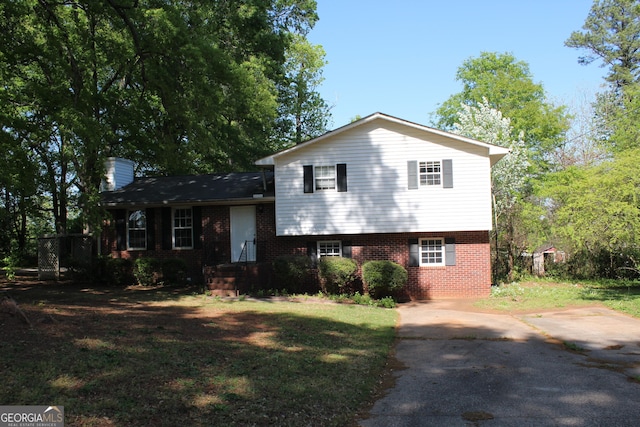 split level home with a chimney, a front lawn, and brick siding