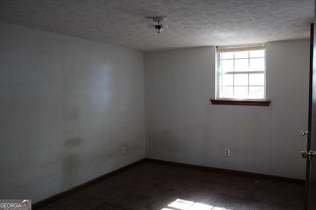 empty room with carpet floors, baseboards, and a textured ceiling