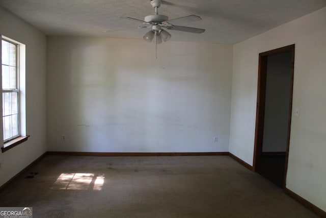 carpeted spare room with visible vents, baseboards, and ceiling fan