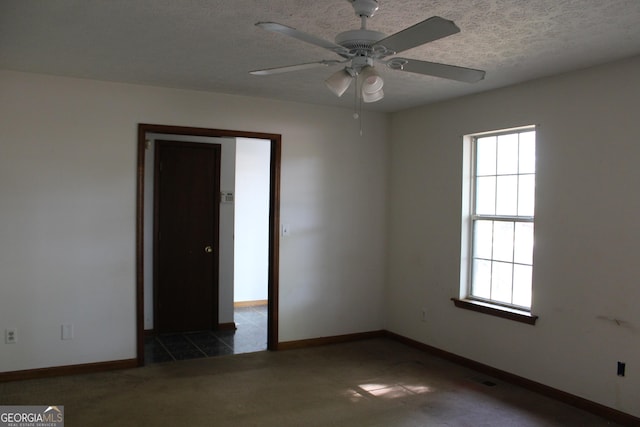 spare room featuring a textured ceiling, a wealth of natural light, baseboards, and ceiling fan