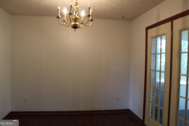 empty room with a chandelier, visible vents, and baseboards