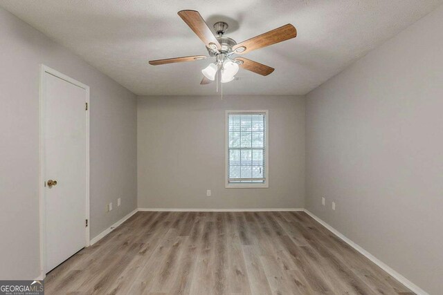 empty room with light wood finished floors, baseboards, and a ceiling fan