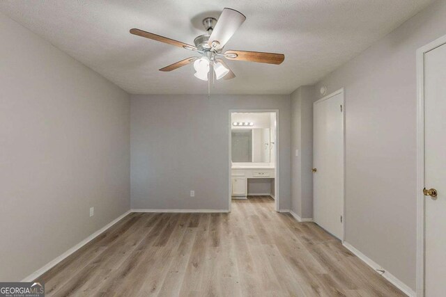 unfurnished bedroom featuring light wood-type flooring, ceiling fan, baseboards, and connected bathroom
