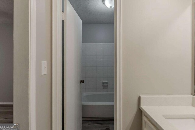 full bath with vanity, wood finished floors, and a textured ceiling