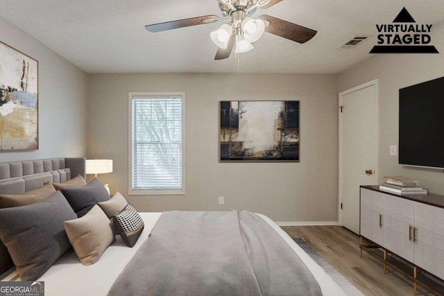 bedroom with wood finished floors, baseboards, a ceiling fan, and visible vents