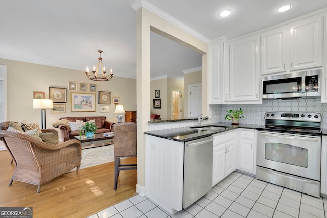 kitchen with a sink, open floor plan, appliances with stainless steel finishes, and a chandelier
