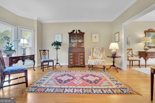 sitting room with baseboards, ornamental molding, and wood finished floors