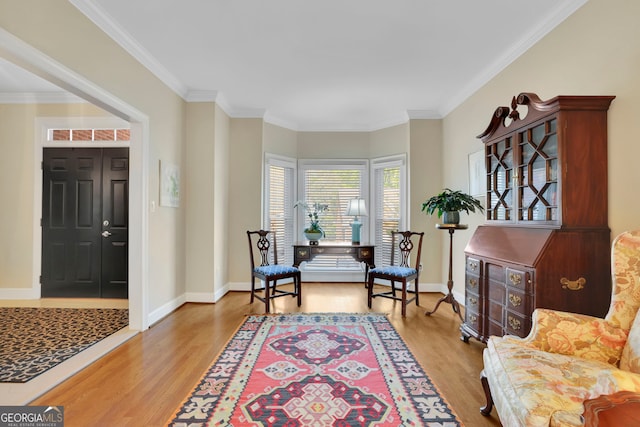 sitting room featuring light wood-style flooring, baseboards, and crown molding