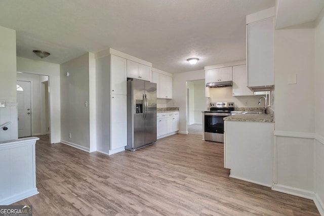 5350 Rockbridge Rd, Stone Mountain, GA 30088 - kitchen with under cabinet range hood, light wood-type flooring, a sink, and appliances with stainless steel finishes