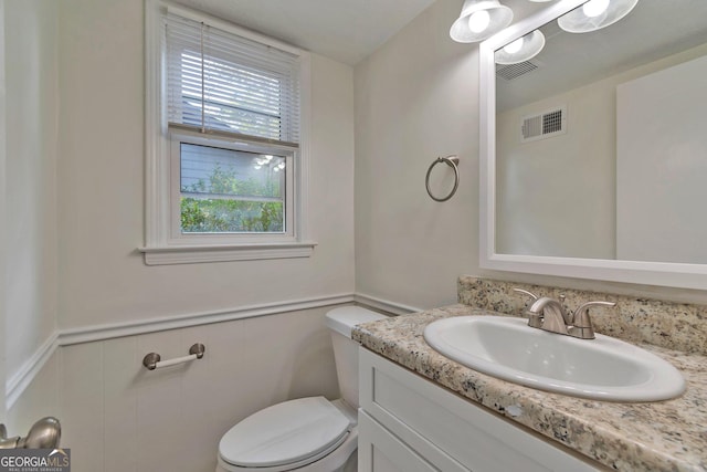 5350 Rockbridge Rd, Stone Mountain, GA 30088 - half bath featuring toilet, vanity, visible vents, and a wainscoted wall