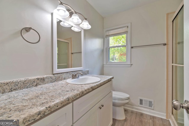 5350 Rockbridge Rd, Stone Mountain, GA 30088 - bathroom featuring vanity, toilet, visible vents, a shower with shower door, and wood finished floors