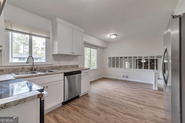 5350 Rockbridge Rd, Stone Mountain, GA 30088 - kitchen with visible vents, white cabinets, a sink, light wood finished floors, and stainless steel appliances