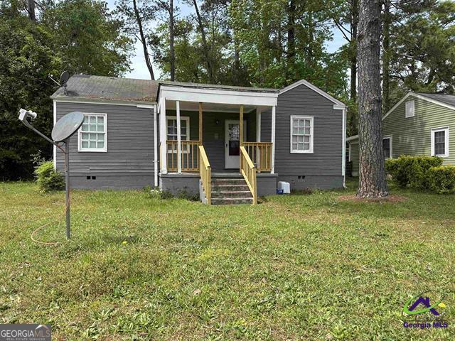 view of front of home featuring a front yard, crawl space, and covered porch