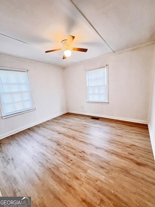 empty room with visible vents, baseboards, ceiling fan, and wood finished floors