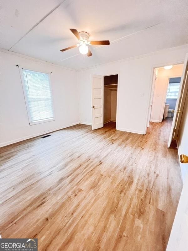 unfurnished bedroom with light wood-style floors, baseboards, multiple windows, and visible vents