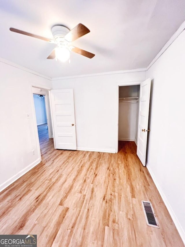unfurnished bedroom featuring baseboards, a closet, ornamental molding, light wood-style floors, and visible vents