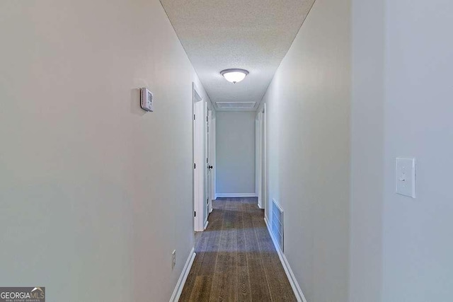 corridor featuring visible vents, baseboards, carpet flooring, and a textured ceiling