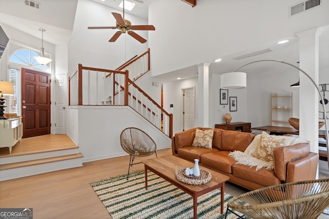 living room featuring wood finished floors, ceiling fan, visible vents, and stairs