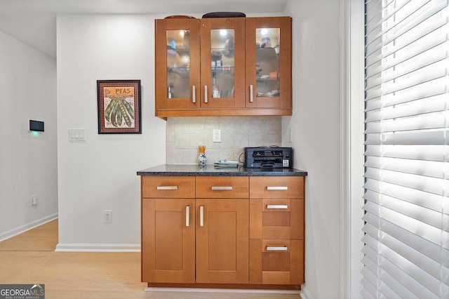 bar featuring light wood-style flooring, decorative backsplash, and baseboards