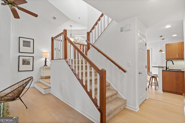stairway featuring ceiling fan with notable chandelier, visible vents, recessed lighting, wood finished floors, and baseboards