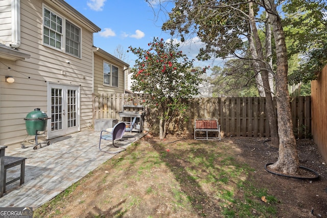 view of yard featuring french doors, a fenced backyard, and a patio