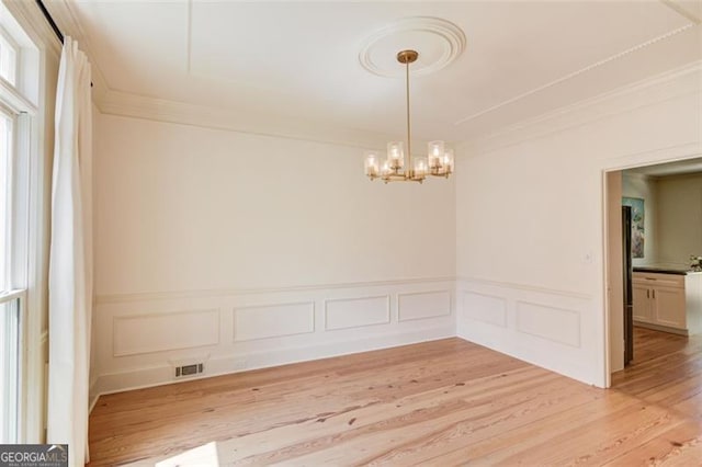 1038 Huntcliff, Atlanta, GA 30350 - unfurnished dining area featuring a notable chandelier, light wood-style flooring, crown molding, wainscoting, and a decorative wall