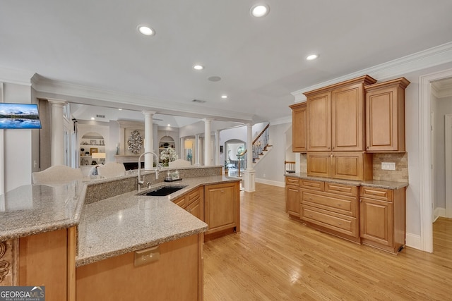 kitchen featuring crown molding, decorative columns, a sink, and baseboards