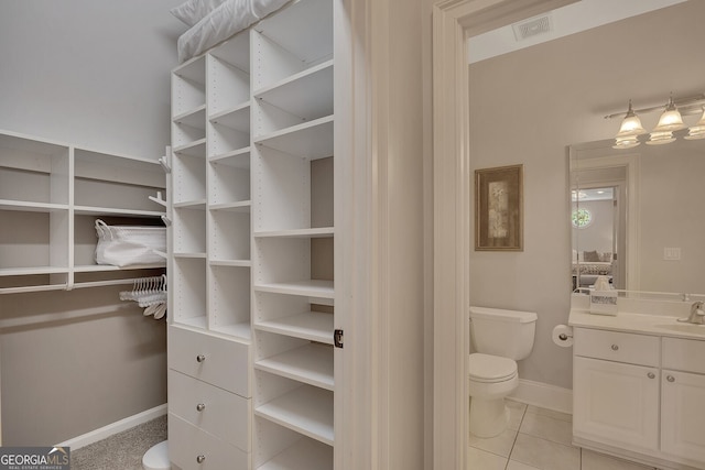 spacious closet featuring light tile patterned flooring, a sink, and visible vents