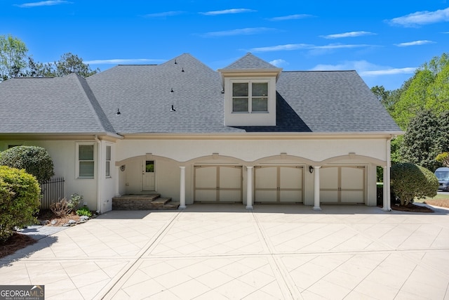 view of front of house with concrete driveway, roof with shingles, fence, and stucco siding