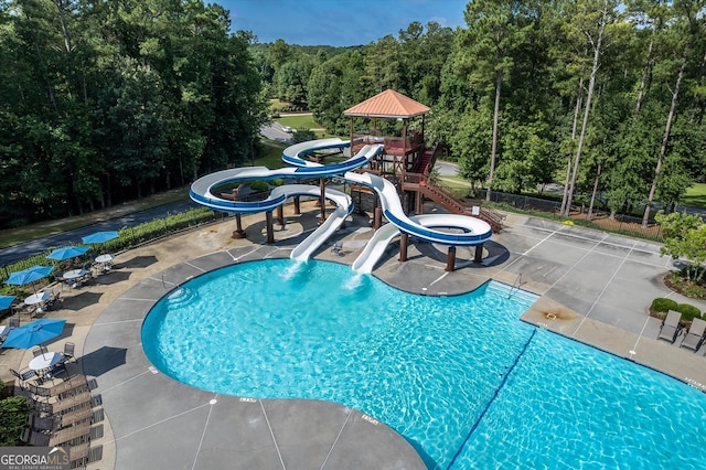 community pool featuring a patio, a water slide, and playground community