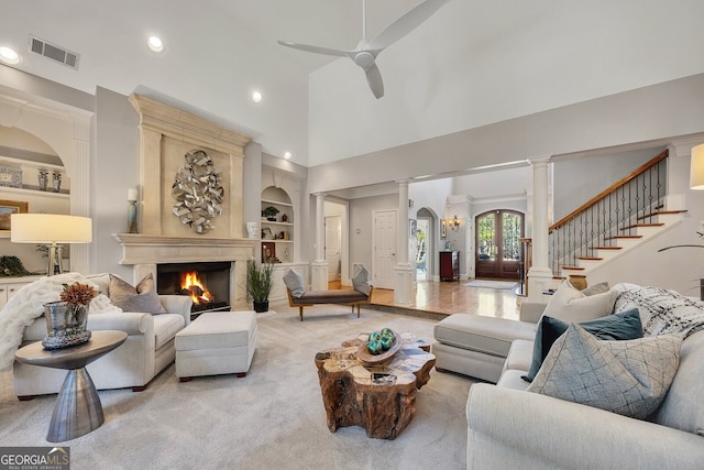 living area featuring built in features, high vaulted ceiling, ceiling fan, visible vents, and a high end fireplace