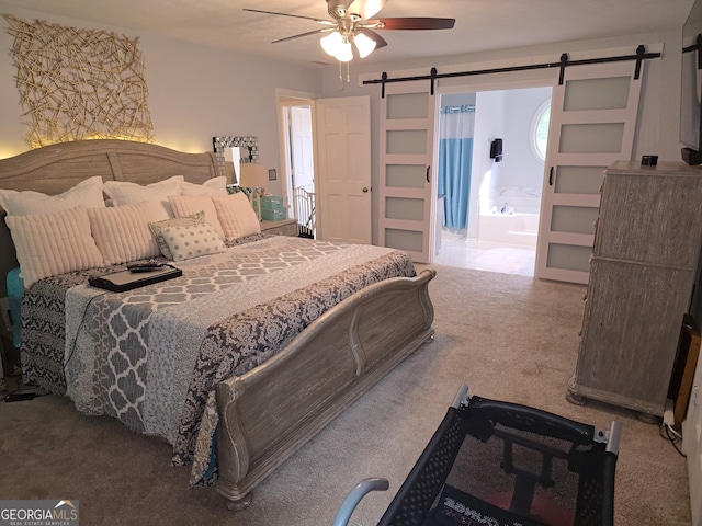 3650 Bay Leaf Dr, Loganville, GA 30052 - carpeted bedroom featuring a barn door, ensuite bath, and a ceiling fan